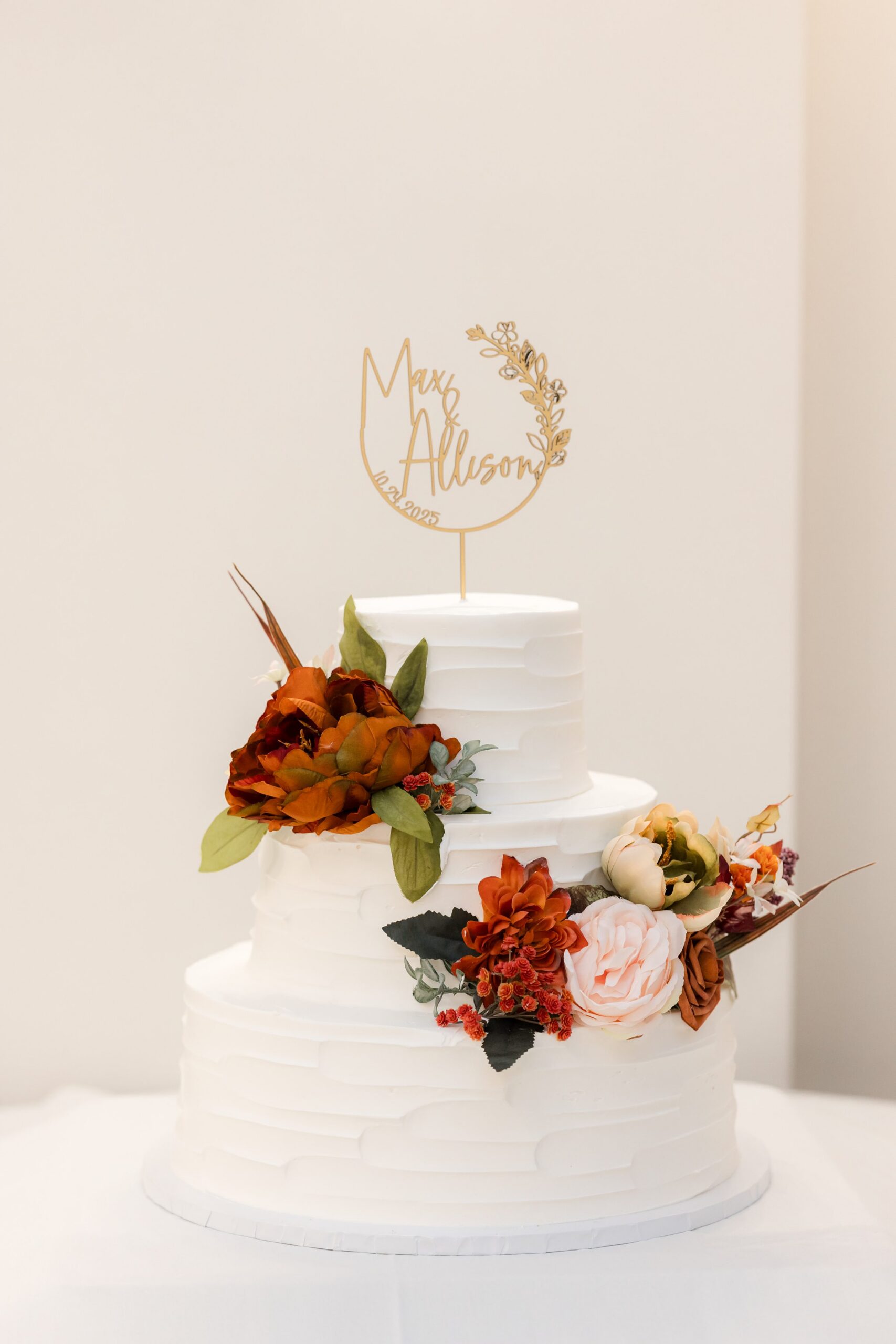 Classic wedding cake adorned with flowers and a personalized topper, symbolizing their union