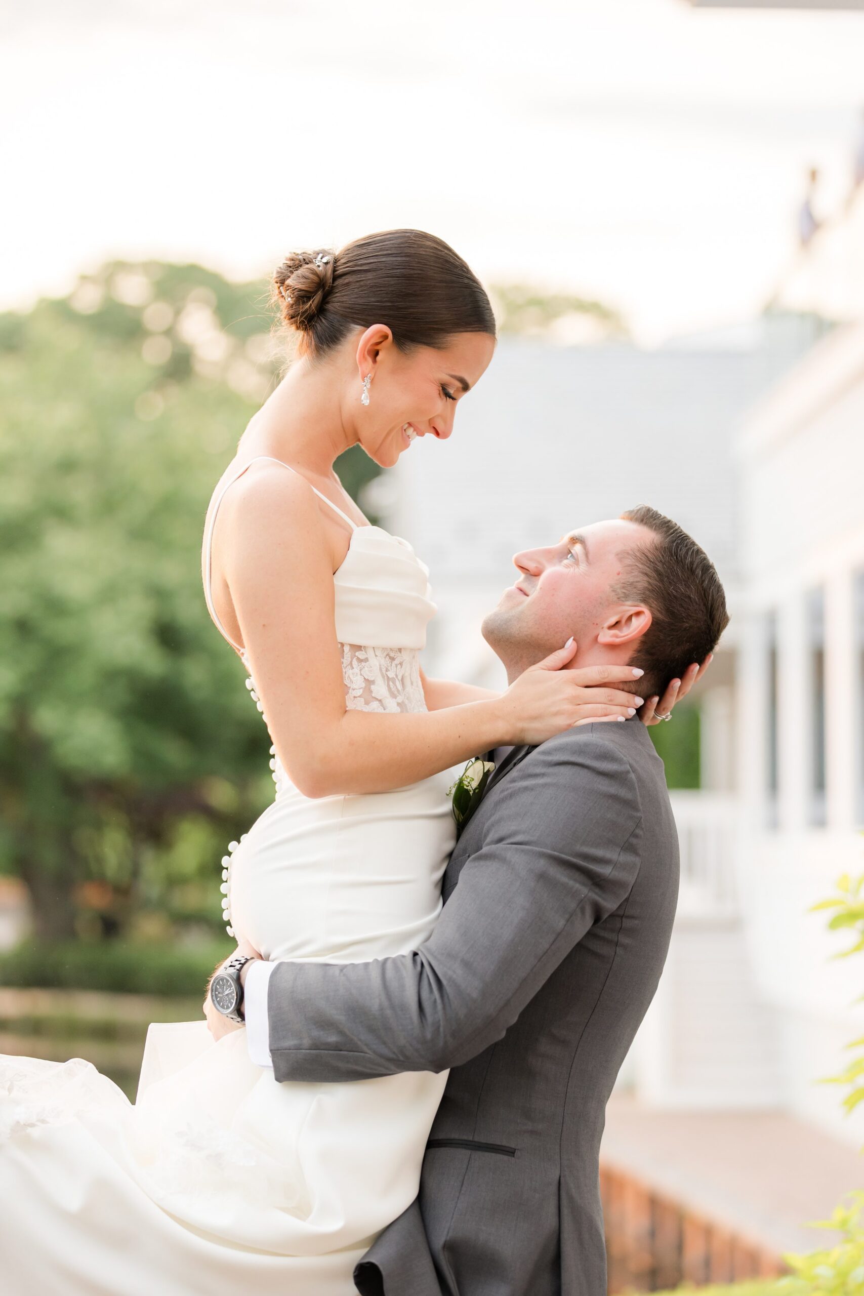 Photo of the couple looking at each other as the groom looks into the bride's eyes while lifting her, and the bride holding the the groom's neck gently, also looking into his eyes