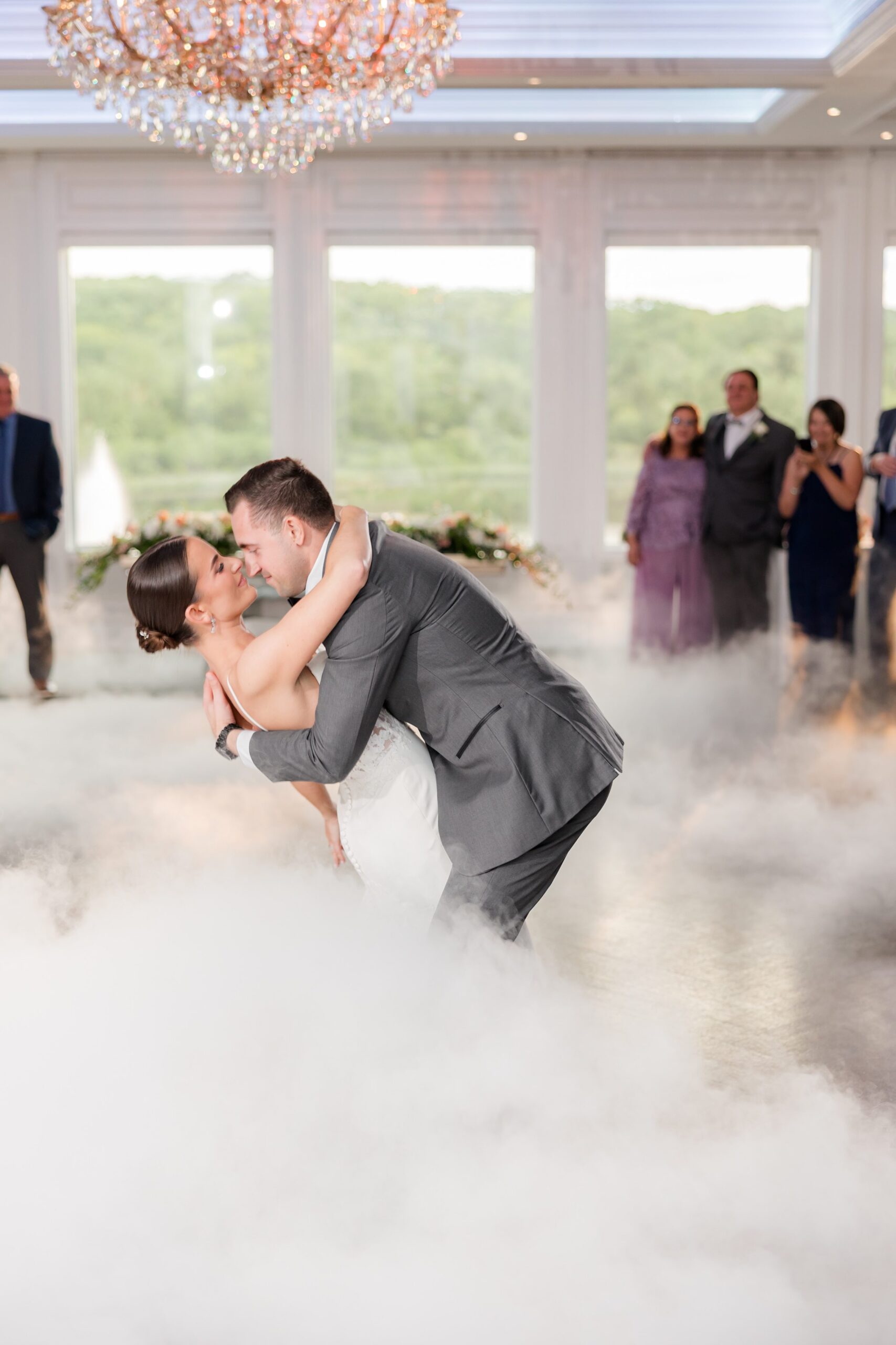 Portrait photo of bride and groom kissing during the first dance on smoke-filled dancefloor