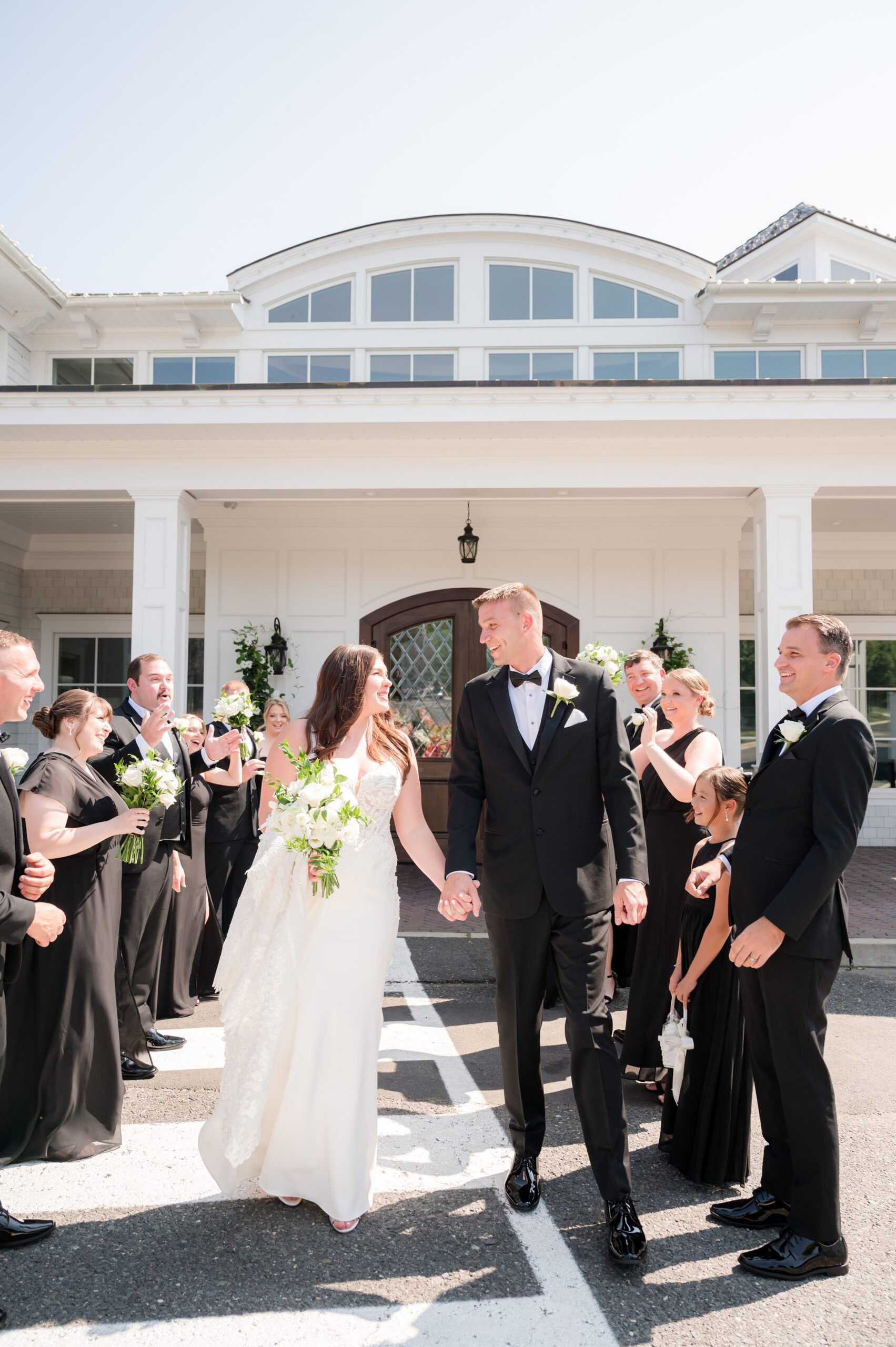 Bride and groom walking together through a joyful crowd of family and friends outside an elegant venue, celebrating just after the ceremony
