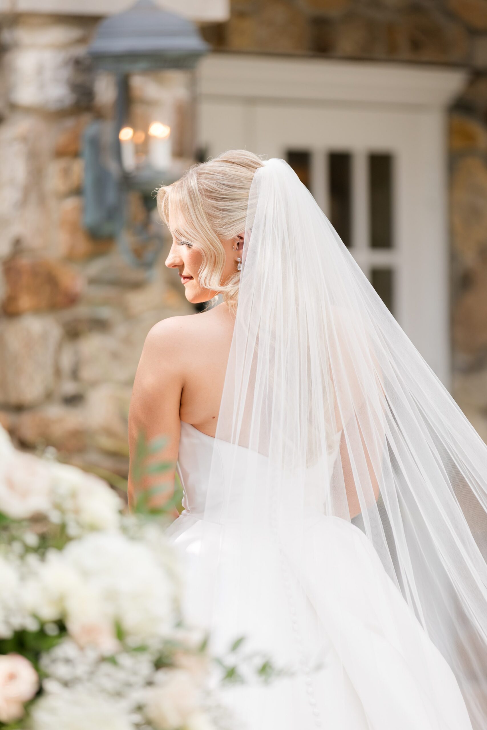 Bride turning back slightly, her veil and bouquet catching the light outside