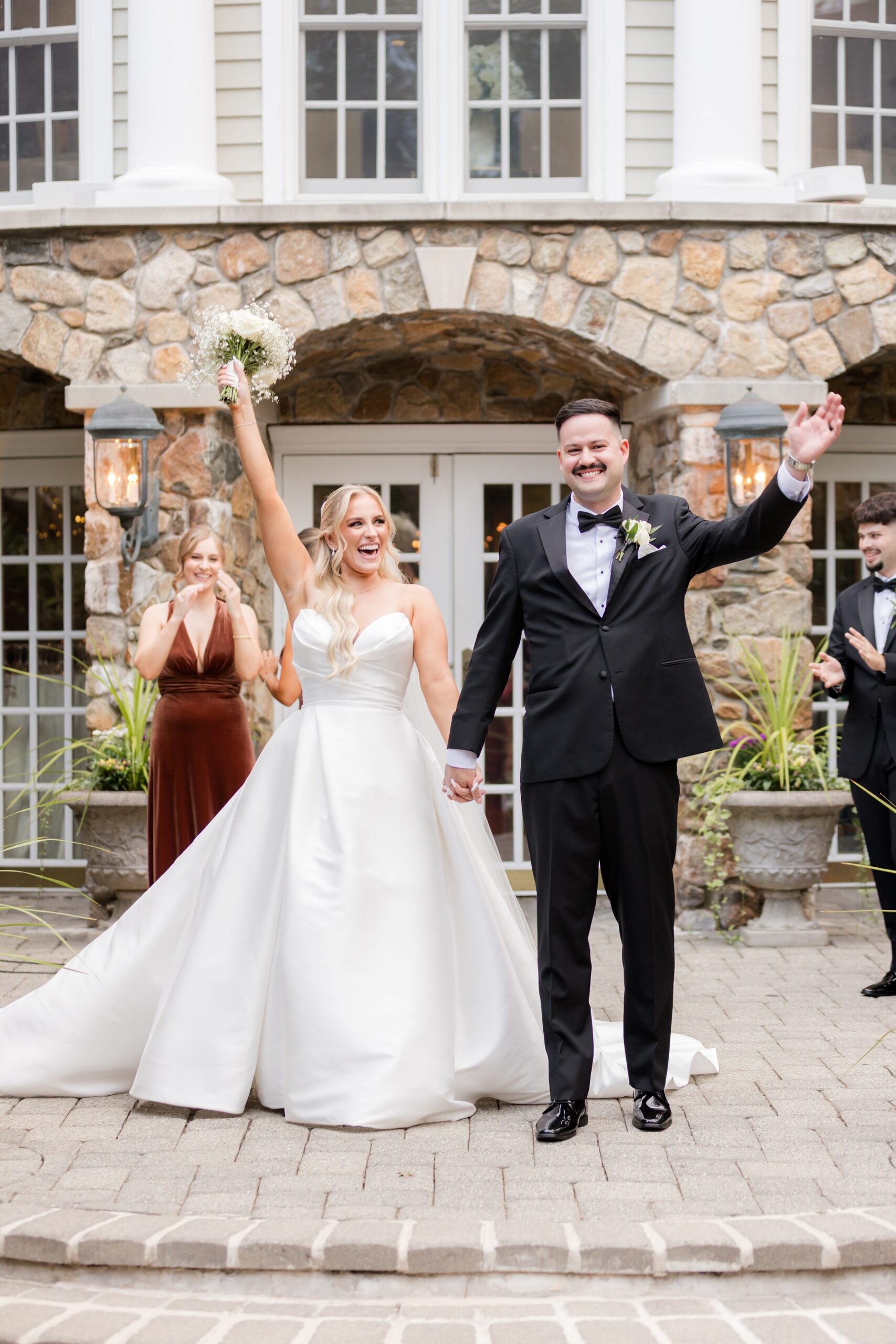 Bride and groom standing together, smiling and raising their hands in celebration after their ceremony