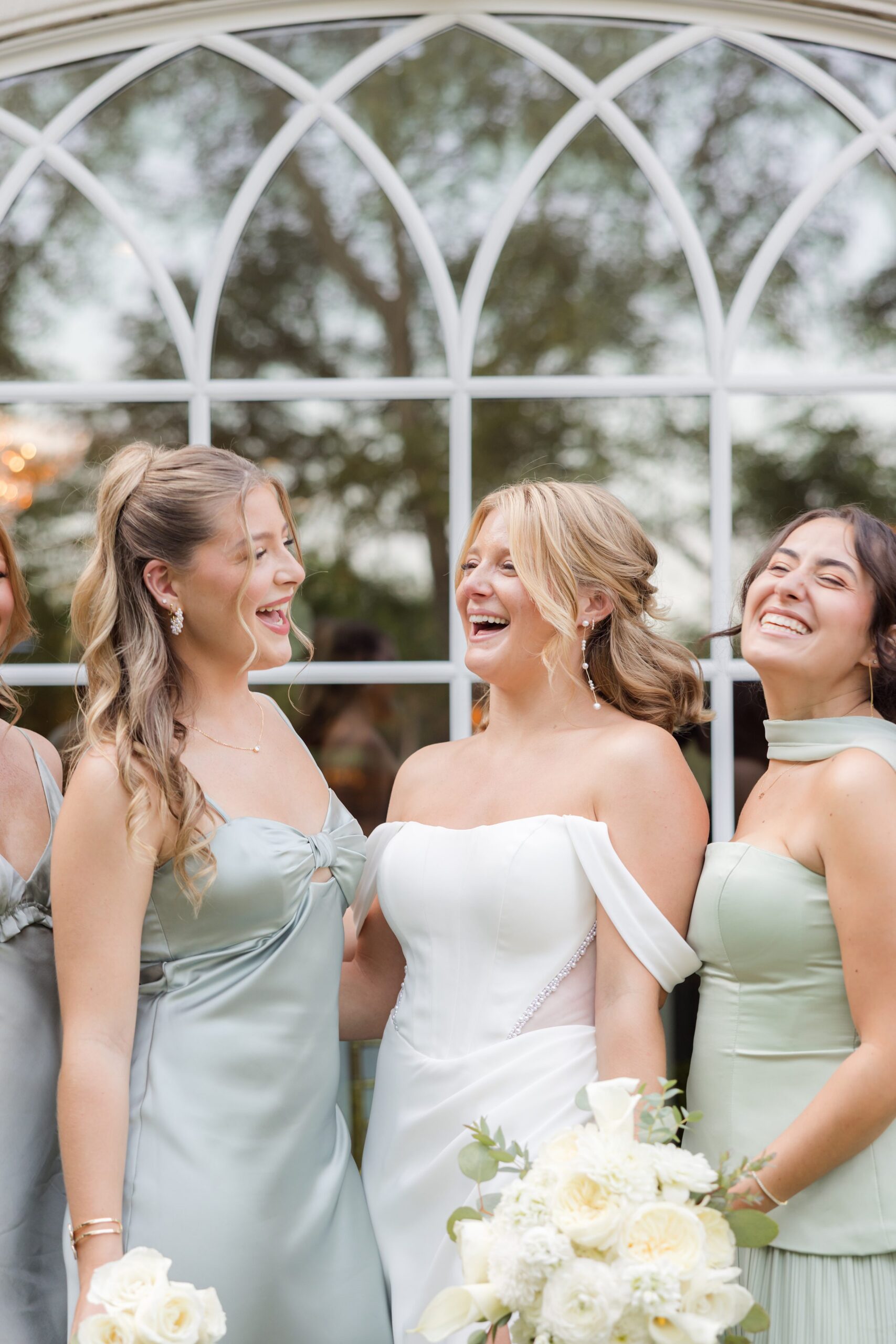 Bride laughs freely with her bridesmaids, captured in a candid moment of happiness and friendship
