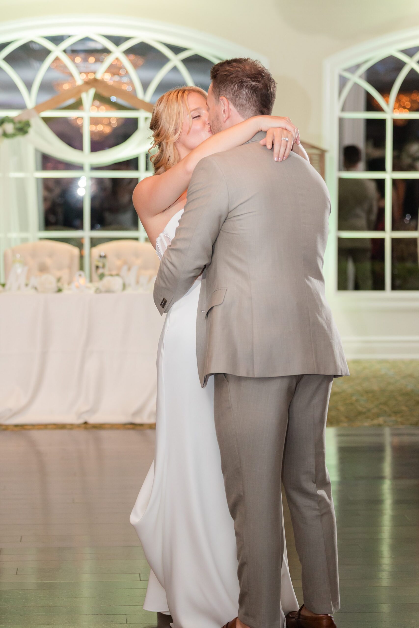 Bride and groom kissing on the dance floor in a softly lit reception space