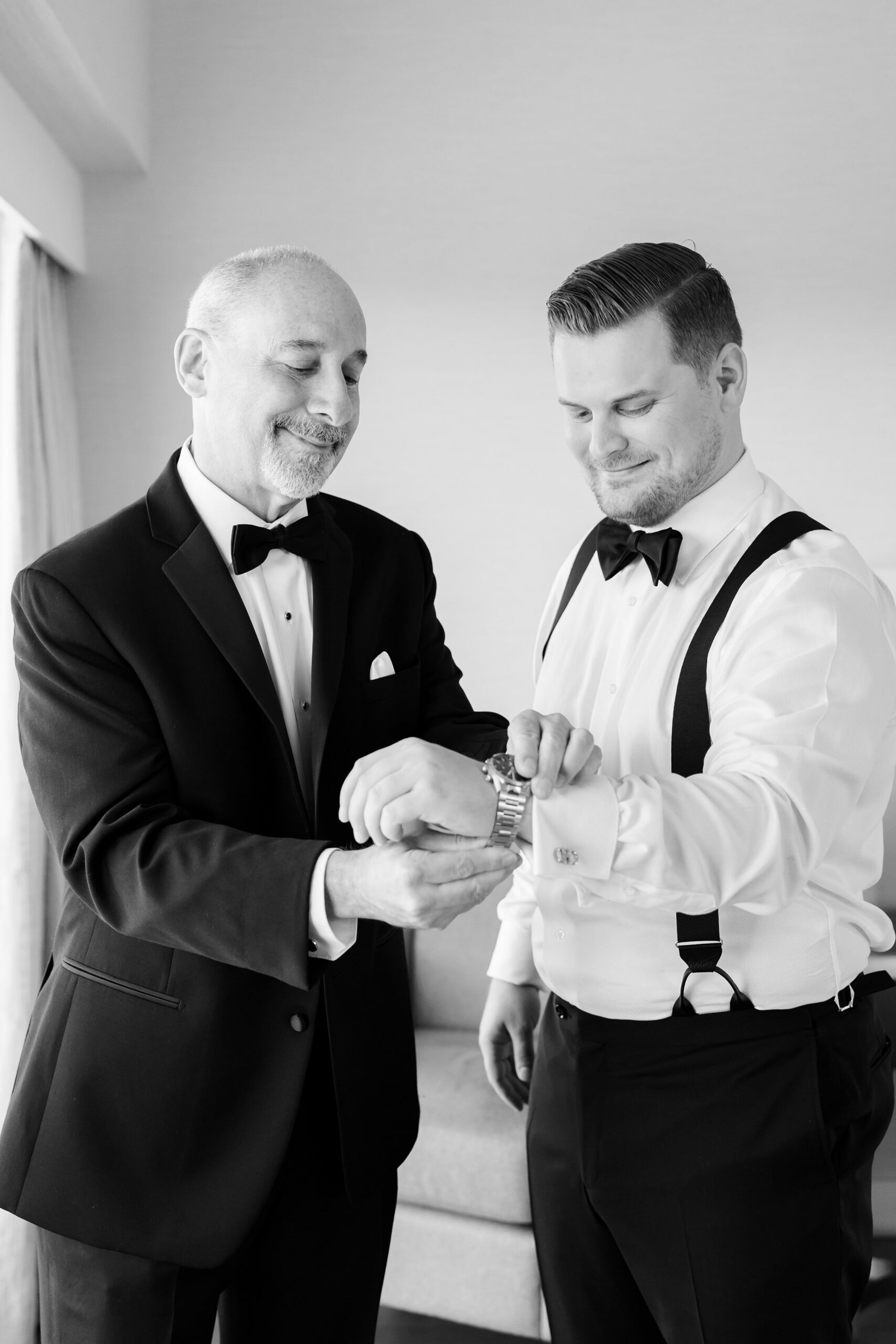 Groom and his father sharing a moment while adjusting cufflinks, both smiling during wedding preparations