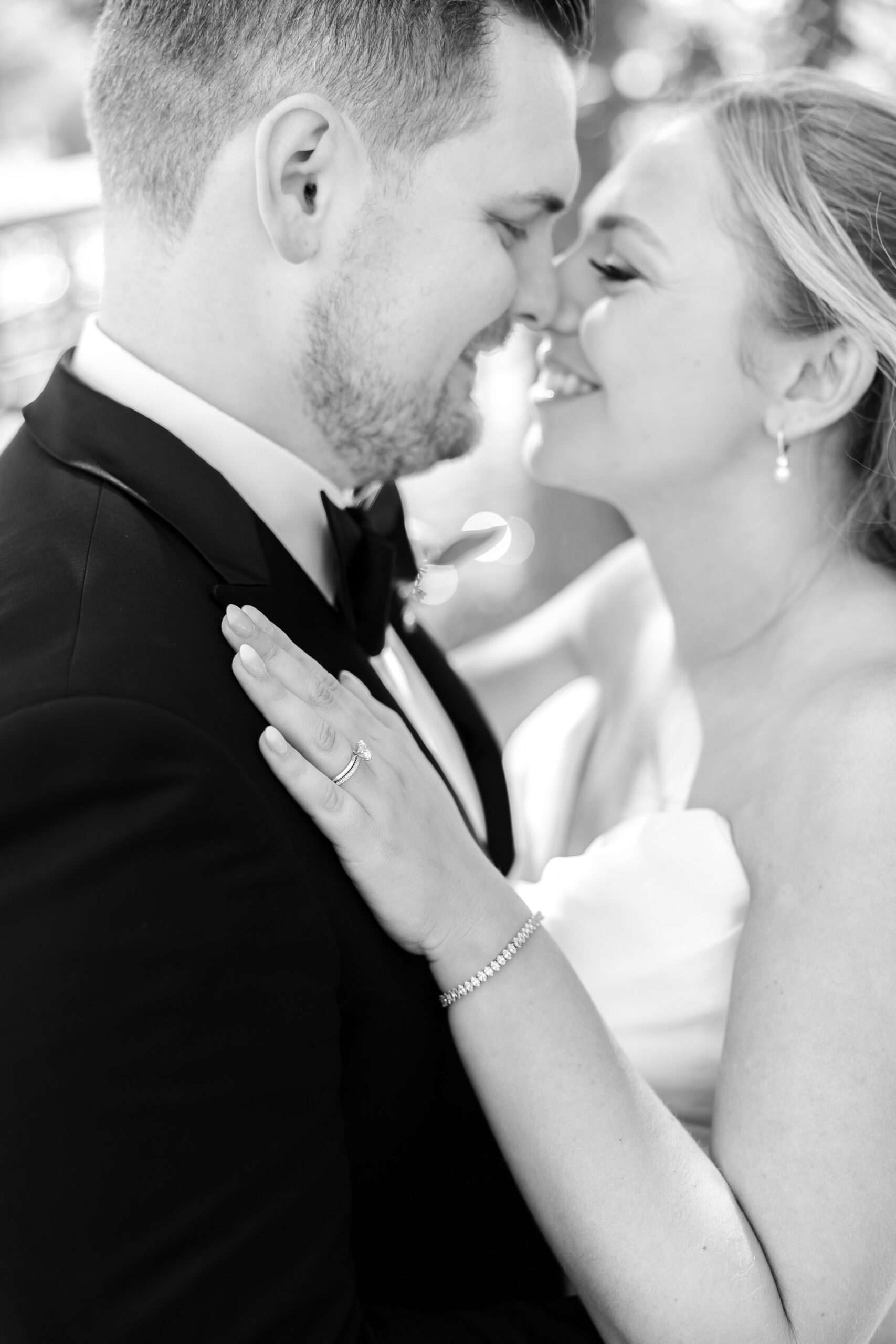 Bride and groom leaning in with foreheads touching, smiling softly, her hand resting on his chest in an intimate, romantic moment