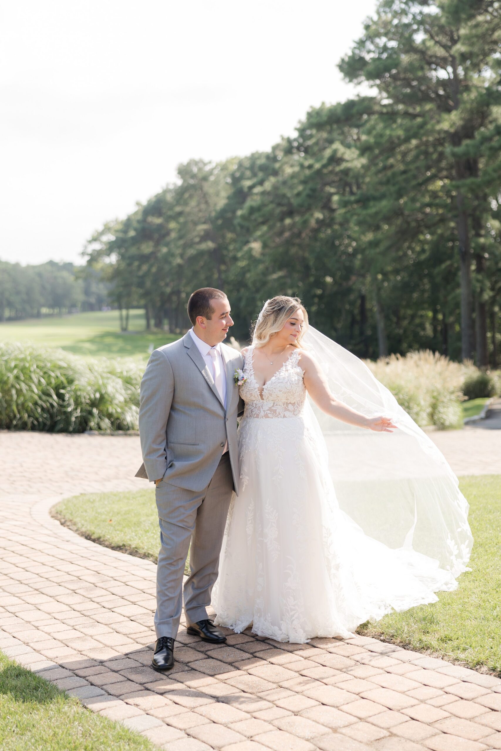 Katherine and Henry standing together on a brick path with the bride’s veil flowing