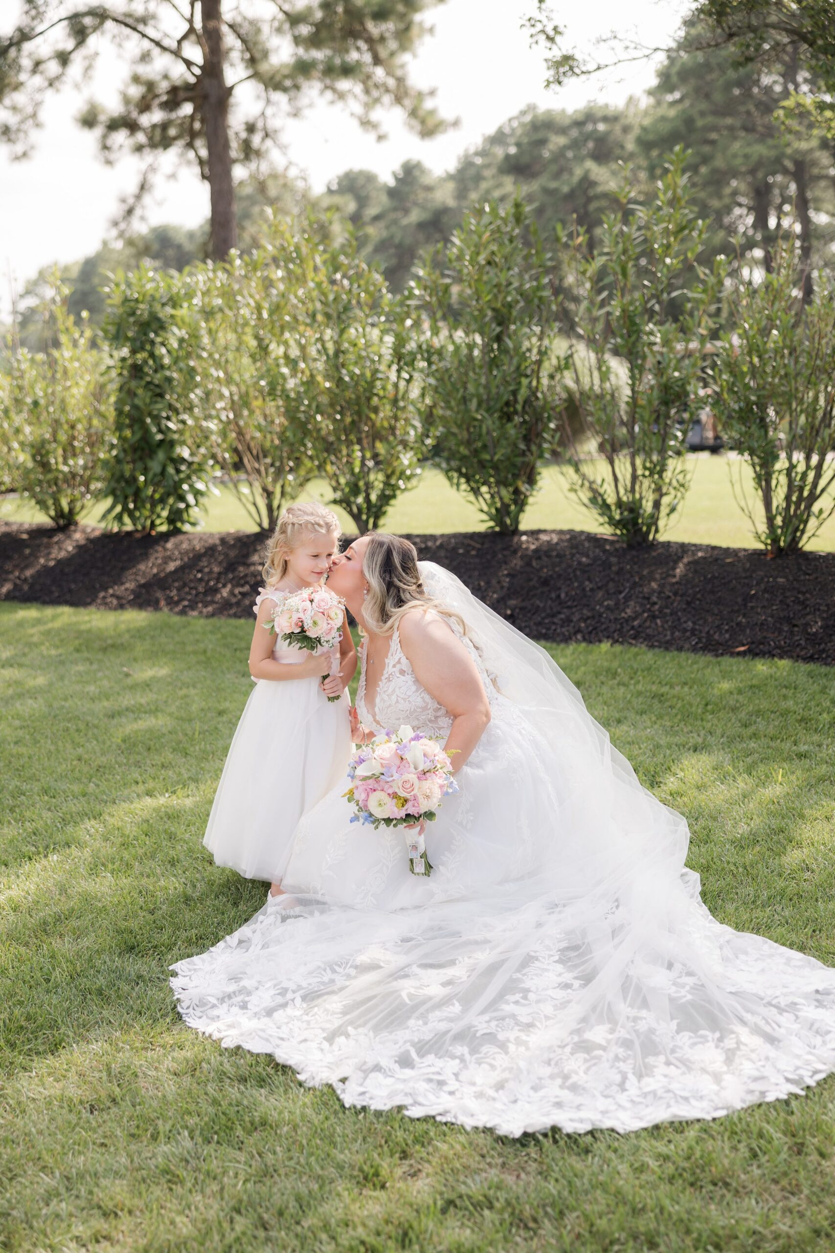 Bride crouching to kiss little bride outdoors