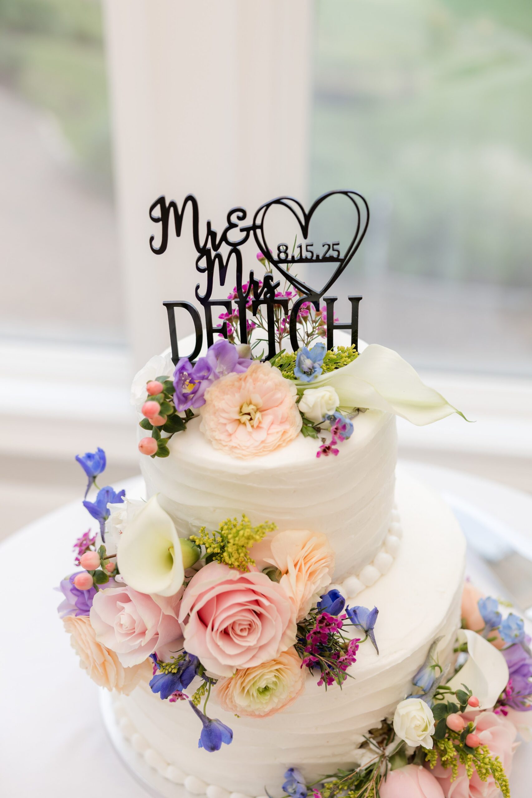 Wedding cake decorated with pastel flowers and a Mr and Mrs topper