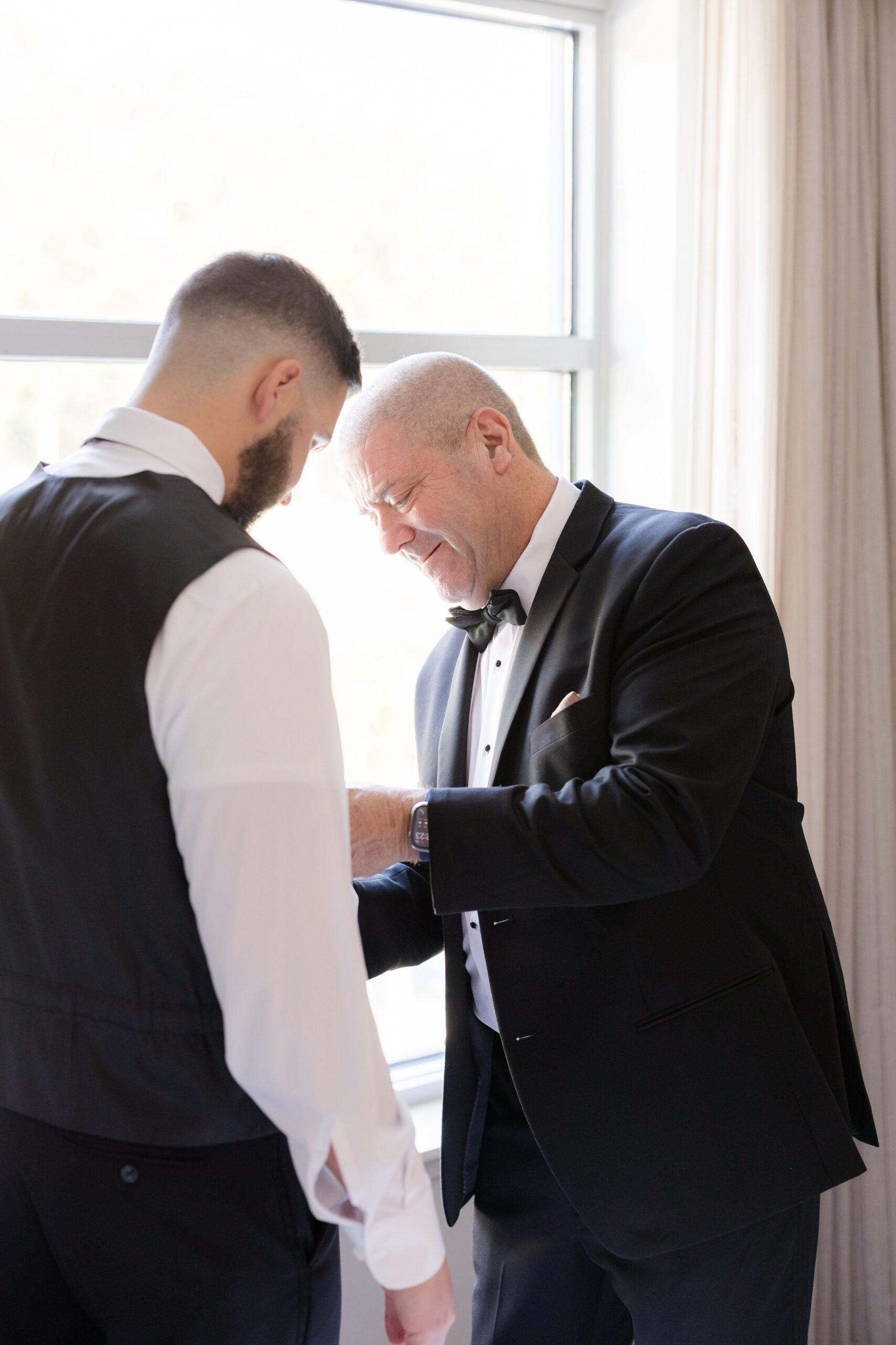 Groom’s father adjusts his sleeve in a quiet, emotional moment before the wedding
