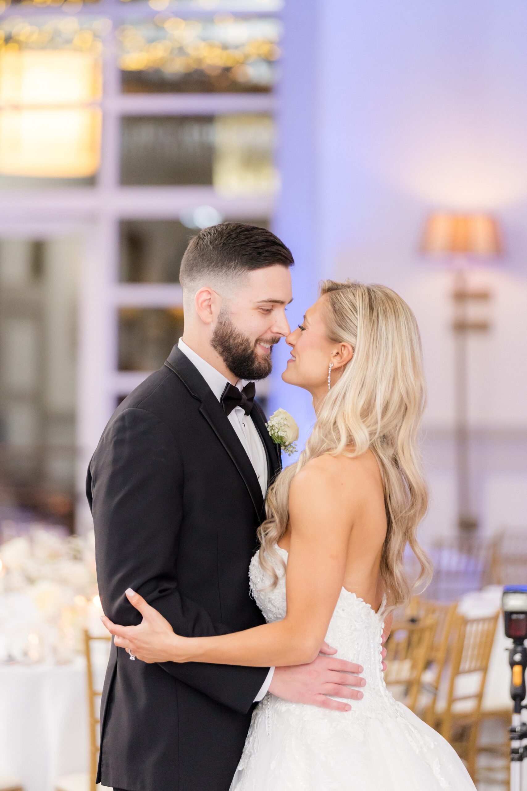 Bride and groom embracing and gazing into each other's eyes at their wedding reception, with a softly lit, elegant indoor setting