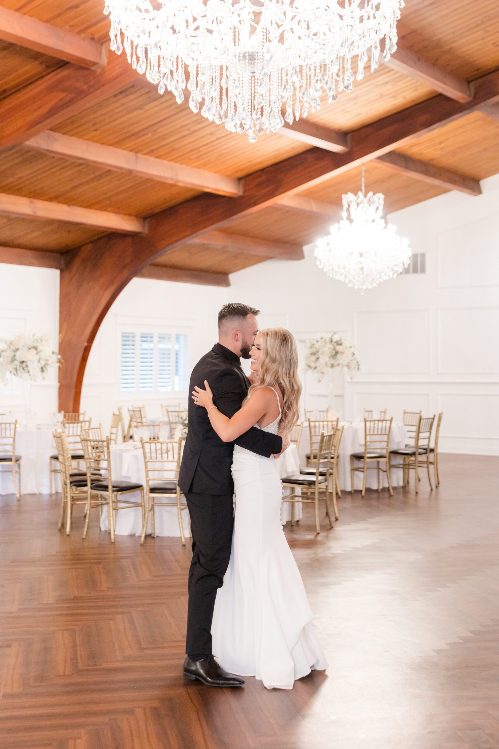 Bride and groom sharing a quiet first dance beneath crystal chandeliers in an elegant reception space