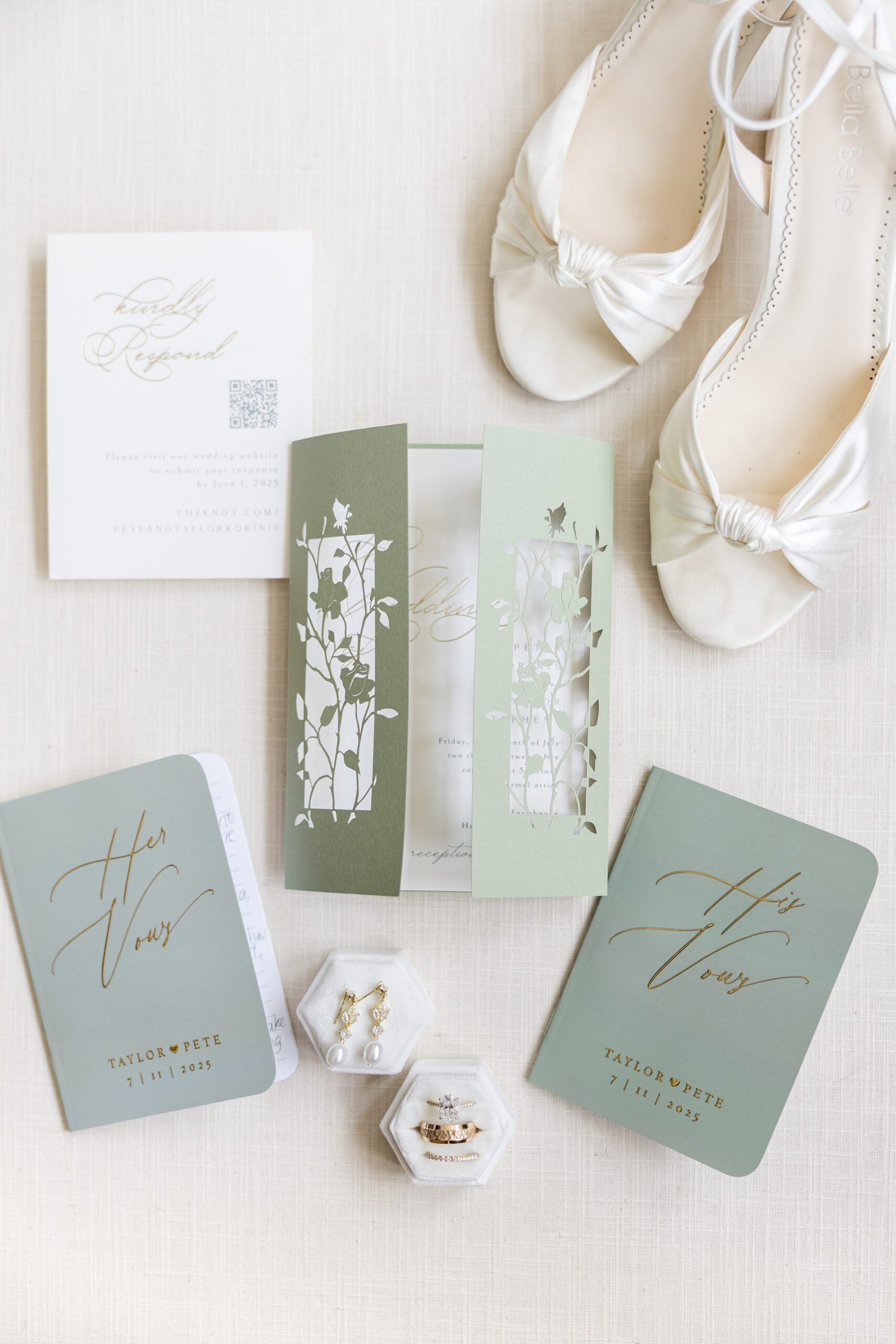 Wedding stationery flat lay with invitation suites, vow books, rings, and bridal shoes arranged on a neutral background