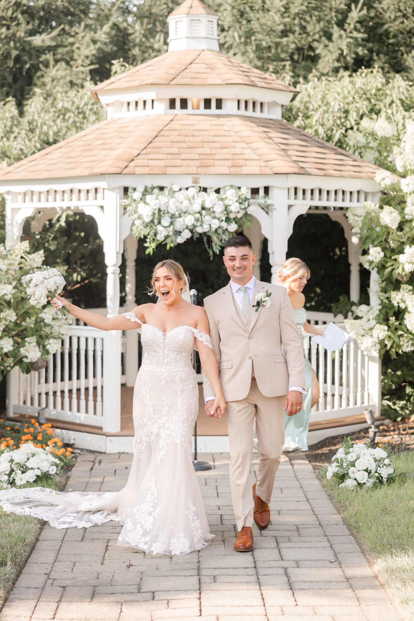 Bride and groom walking together away from the gazebo, smiling and celebrating after their ceremony as guests look on behind them