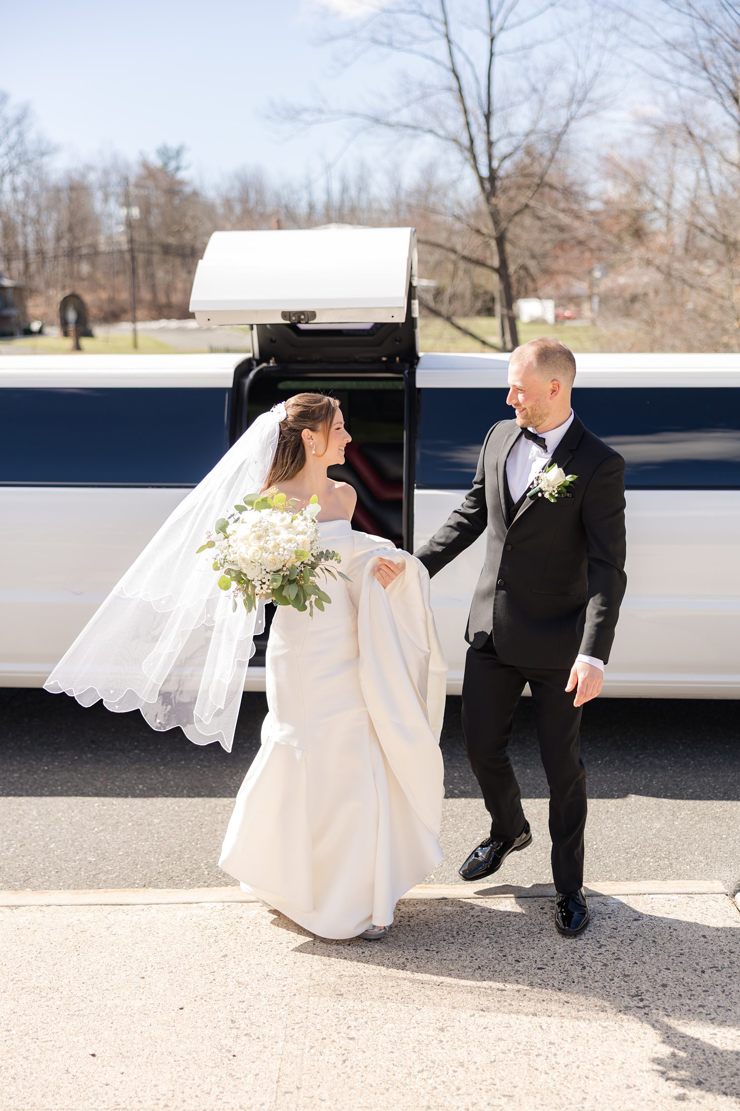 Bride and groom walking outdoors near limousine after ceremony
