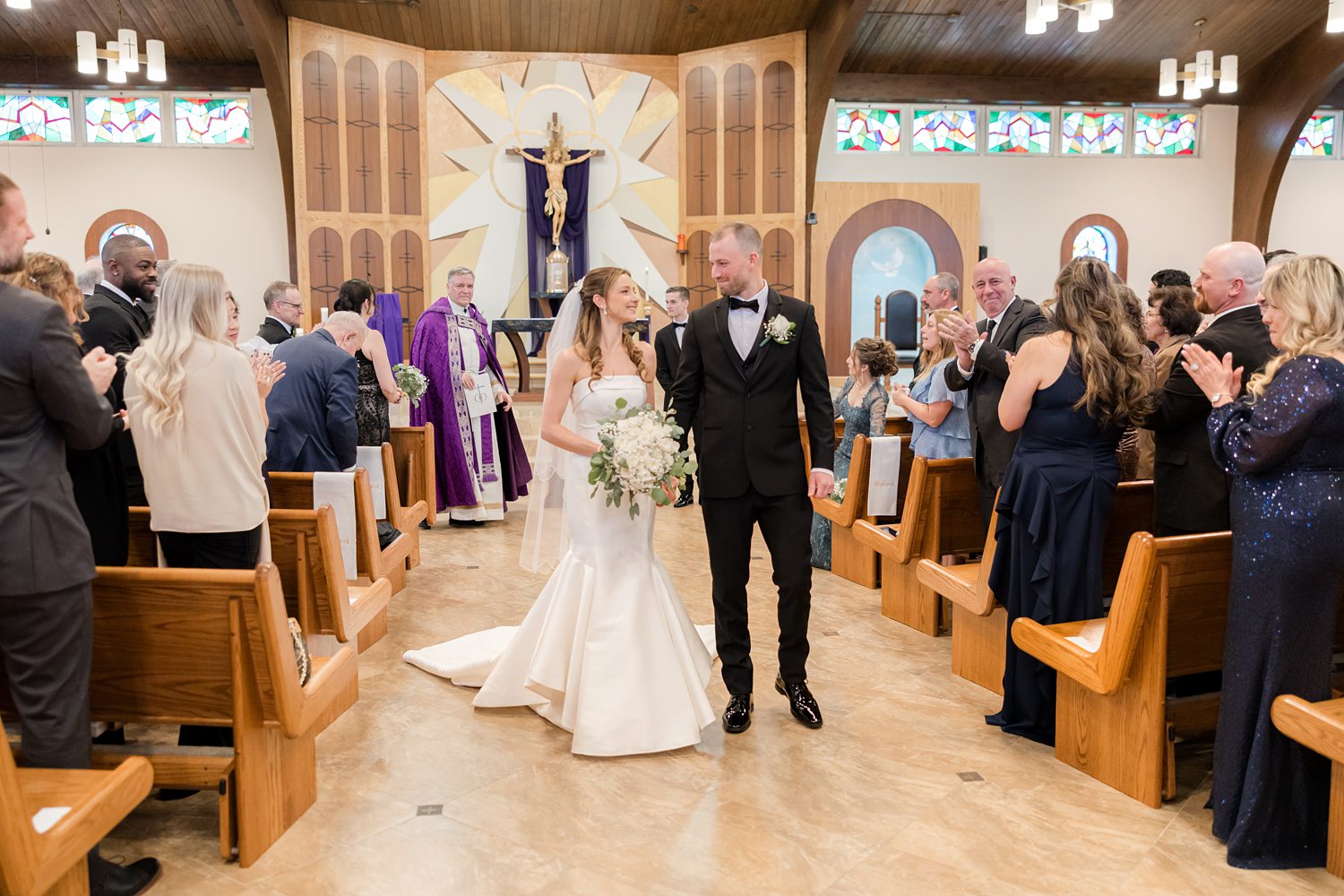 Bride and groom recessed down aisle surrounded by wedding guests