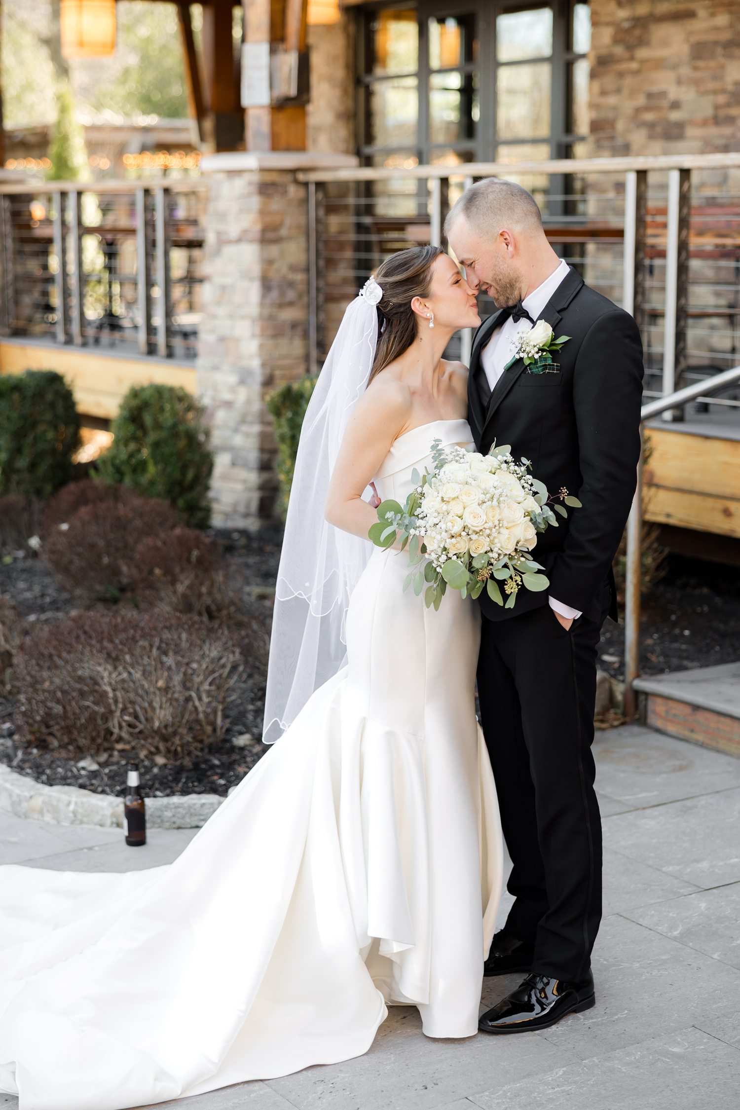 Romantic outdoor wedding portrait with bride and groom kiss