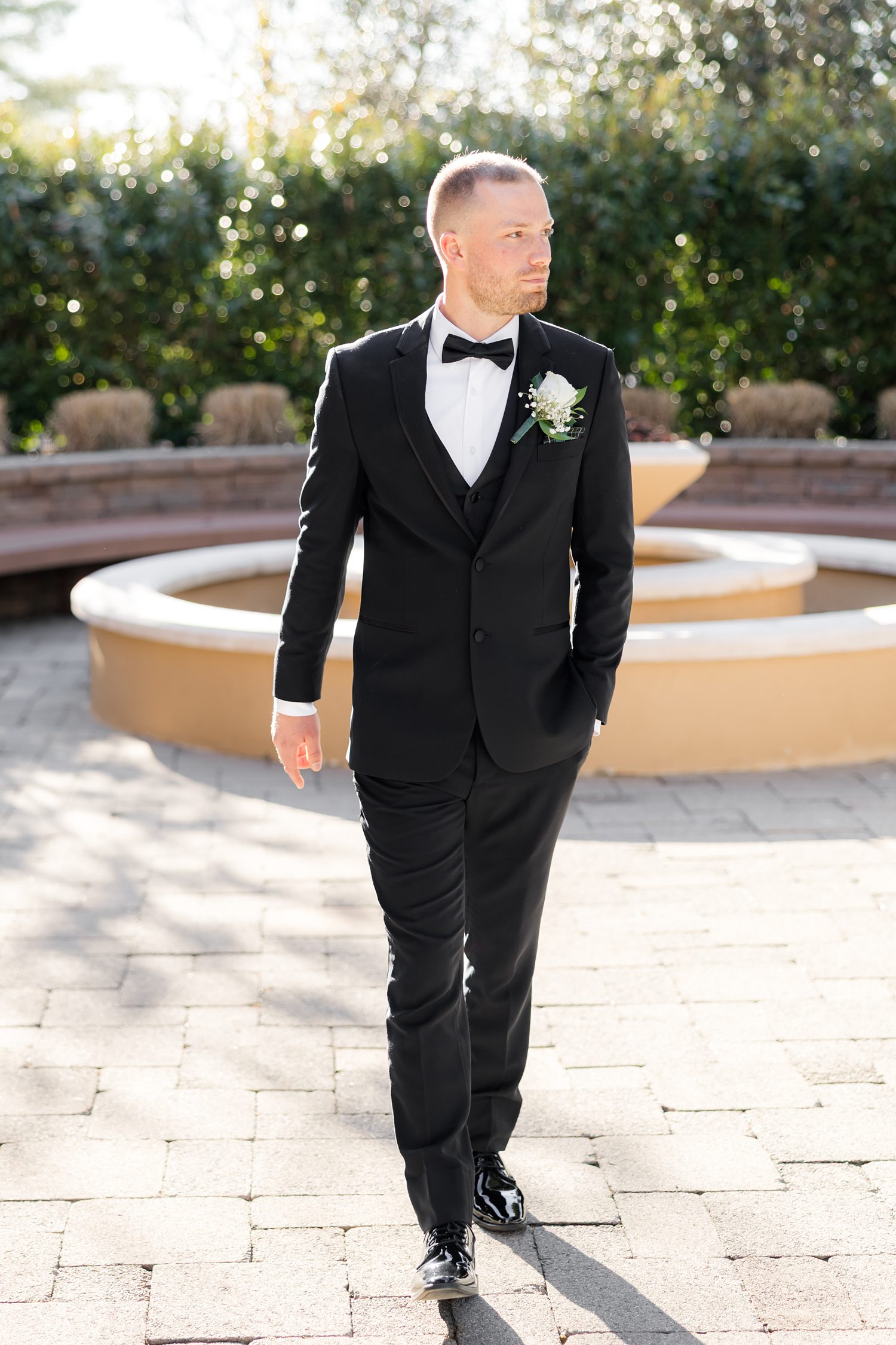 Groom portrait in tuxedo walking outdoors at wedding venue