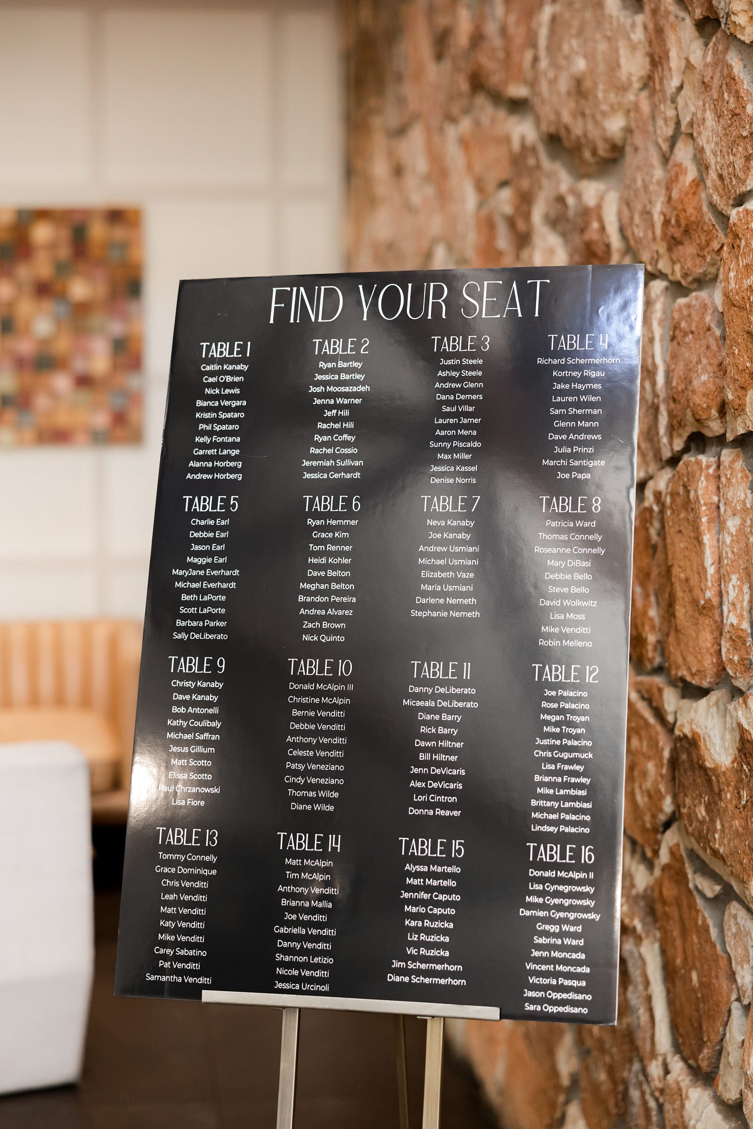 Wedding seating chart display on rustic stone wall at reception entrance