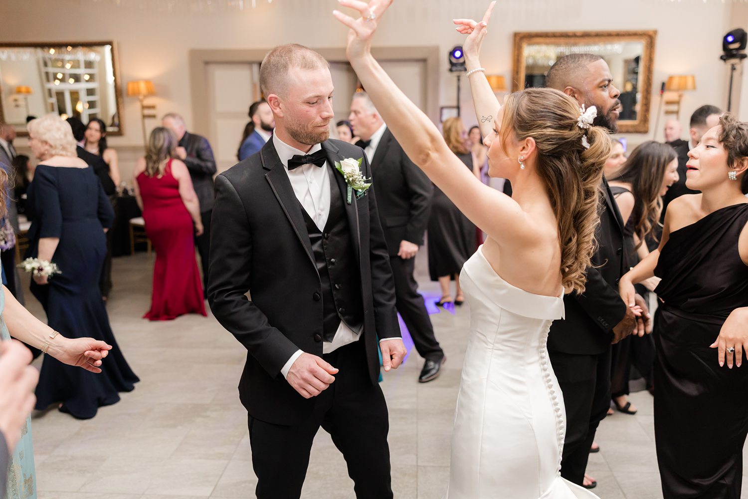 Groom and bride dancing with guests at lively wedding reception