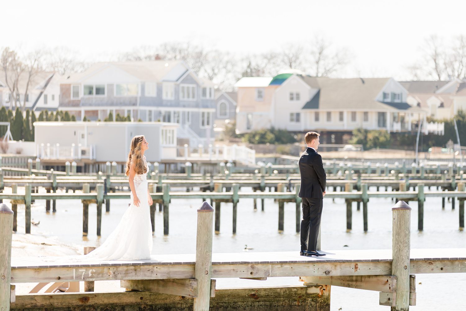 Bride and groom standing together on marina dock during waterfront wedding portraits