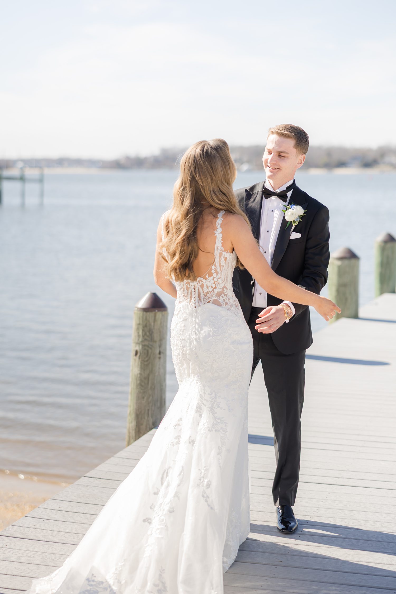 Romantic waterfront wedding portrait of bride and groom embracing on dock