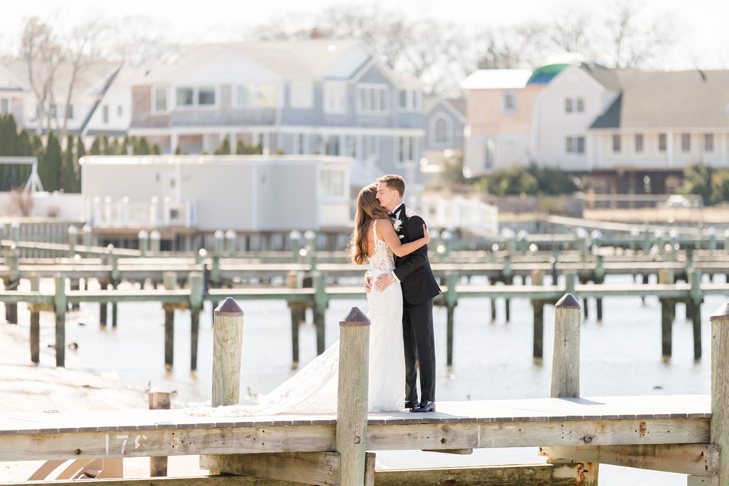 Bride and groom walking together along marina dock at sunset
