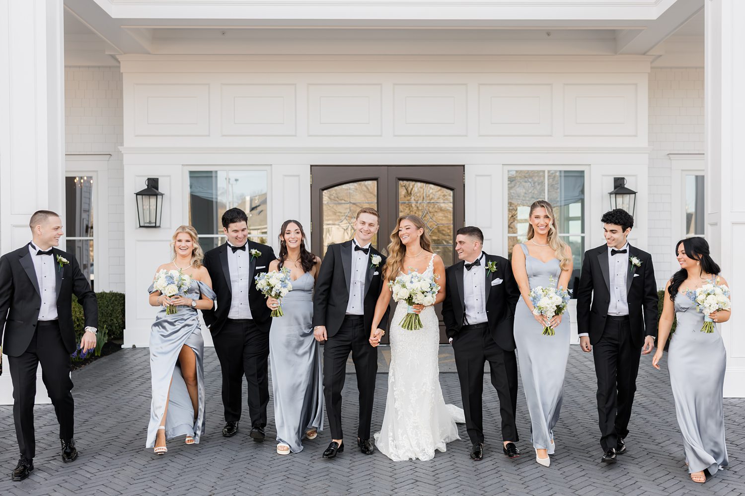 Groomsmen and bridesmaids cheering together outside luxury wedding venue