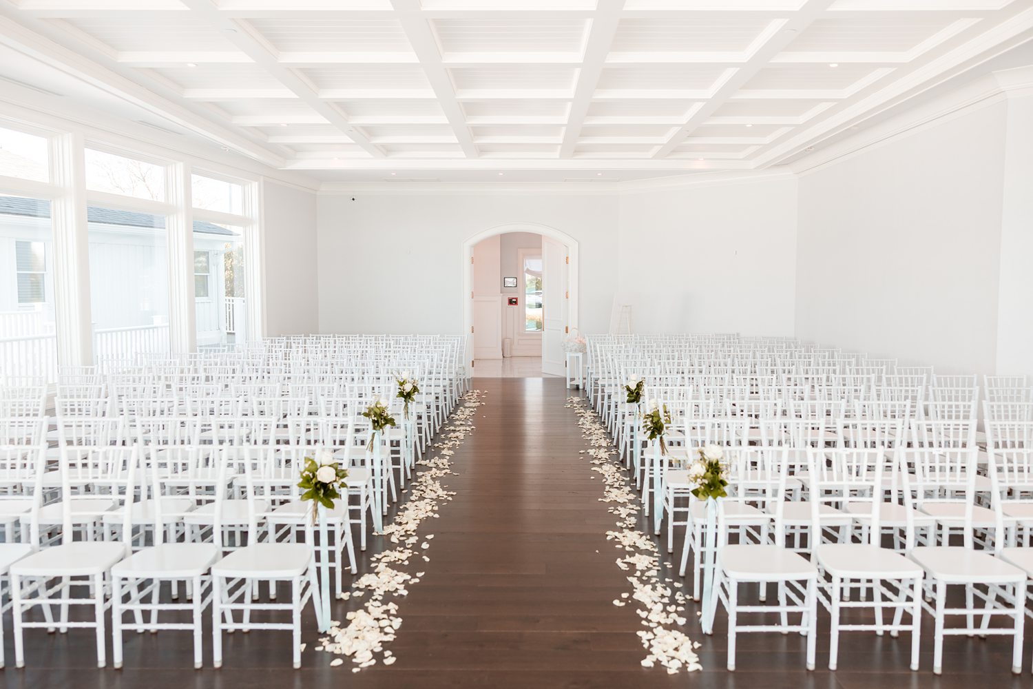 Elegant waterfront wedding ceremony setup with white chairs and floral aisle decor