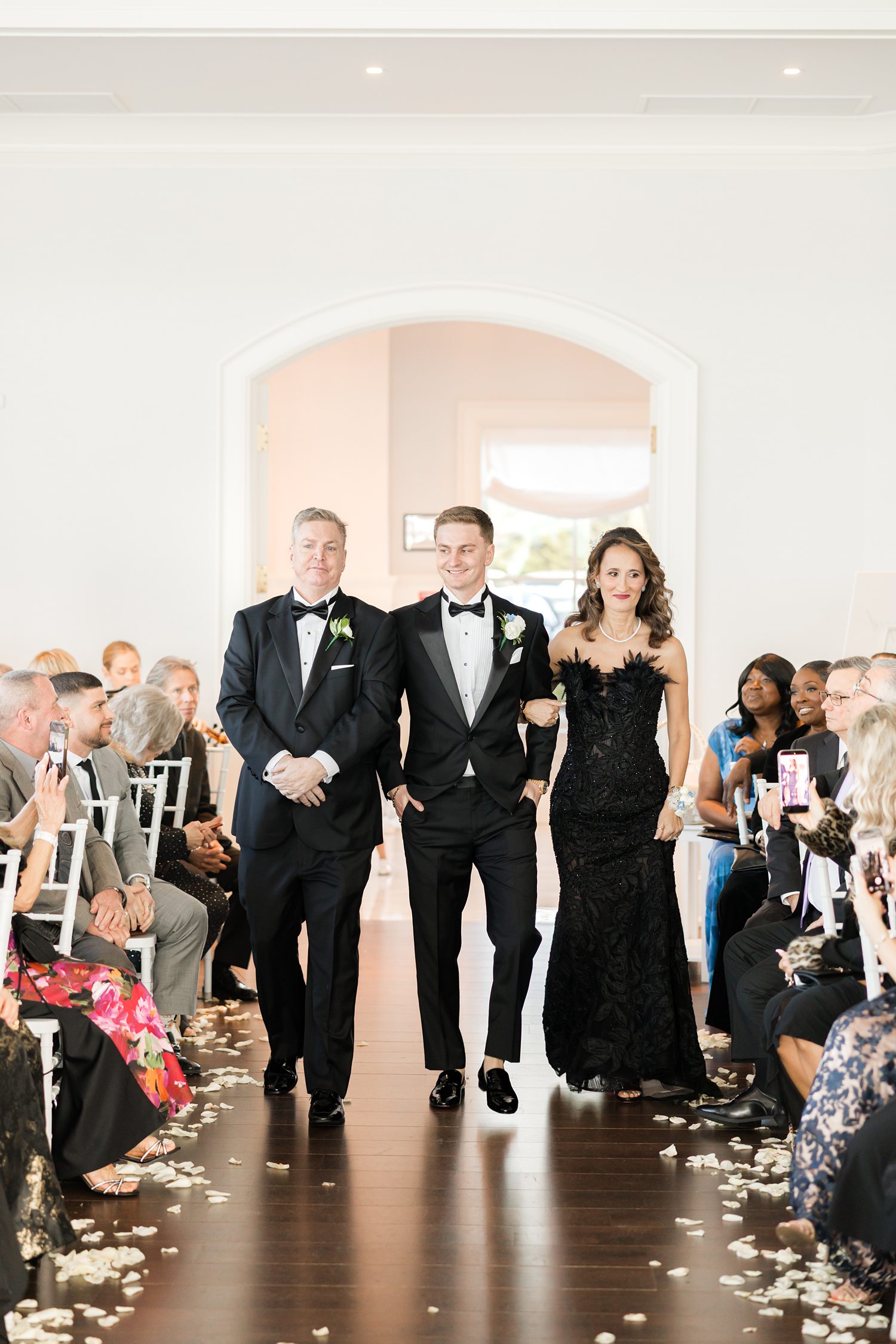 Groom walking his family down aisle during emotional indoor wedding ceremony