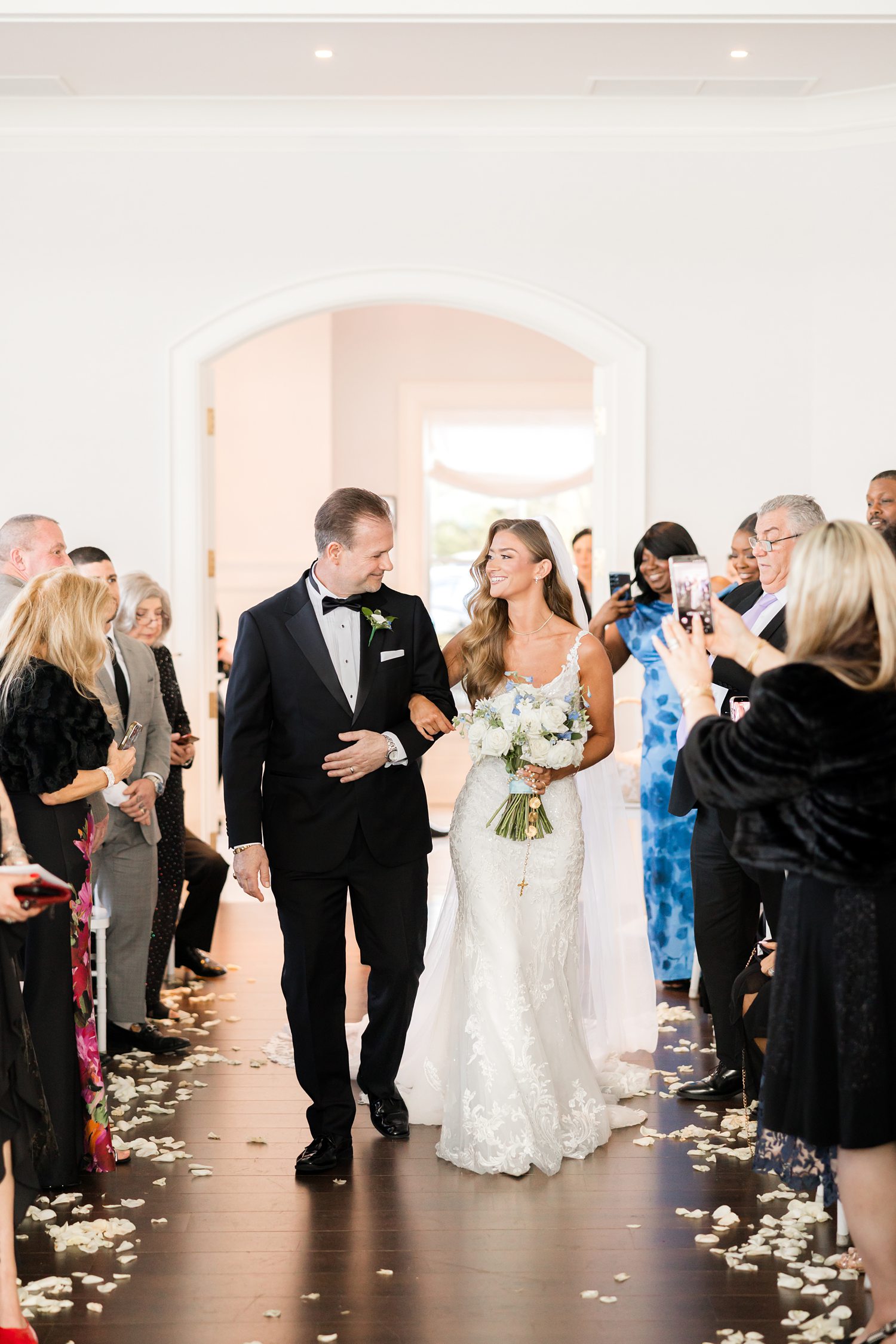 Bride and the father smiling during elegant indoor wedding ceremony processional