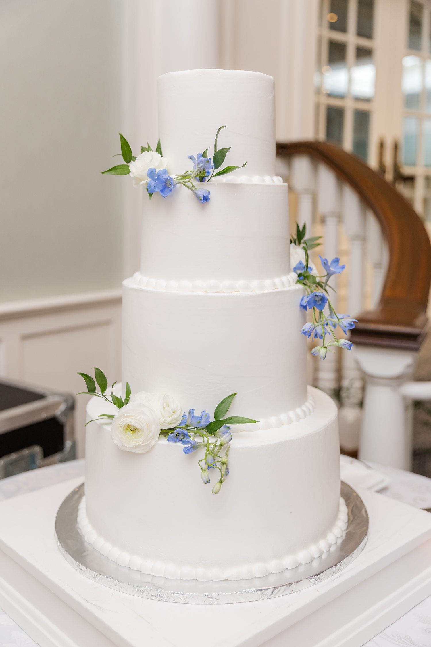Elegant white multi-tier wedding cake with blue floral accents