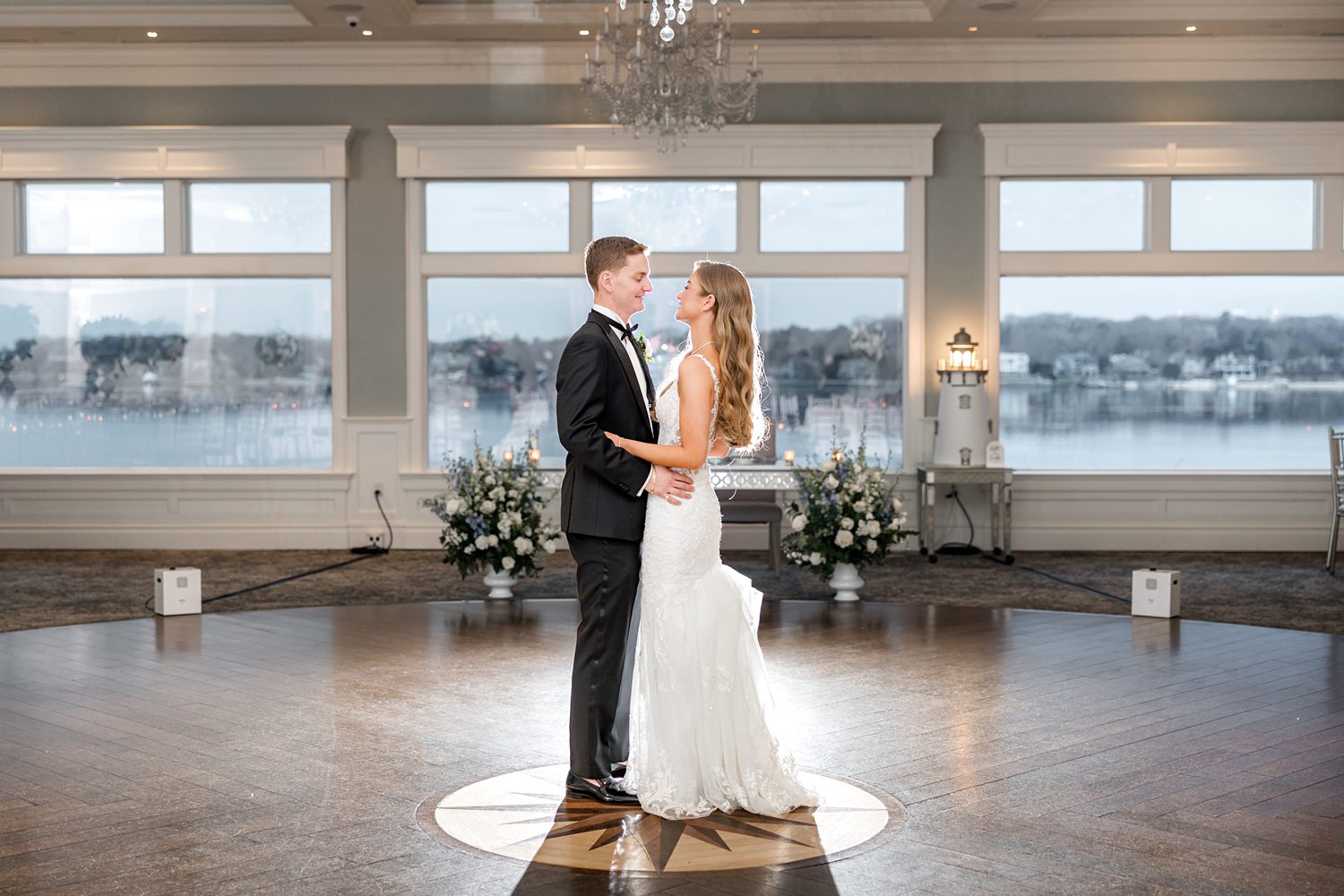 Bride and groom dancing alone in elegant chandelier-lit ballroom