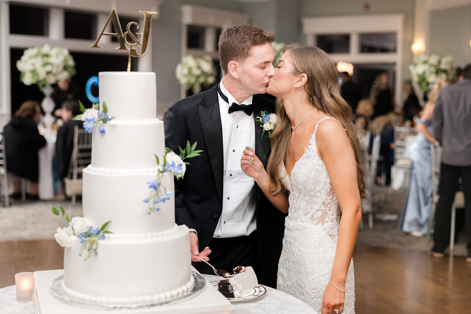Romantic Newlywed couple kissing beside wedding cake during reception