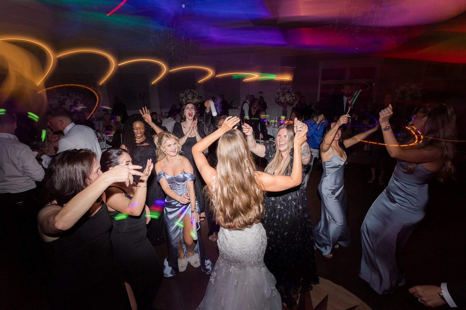 Wedding guests dancing under colorful lights during lively reception celebration