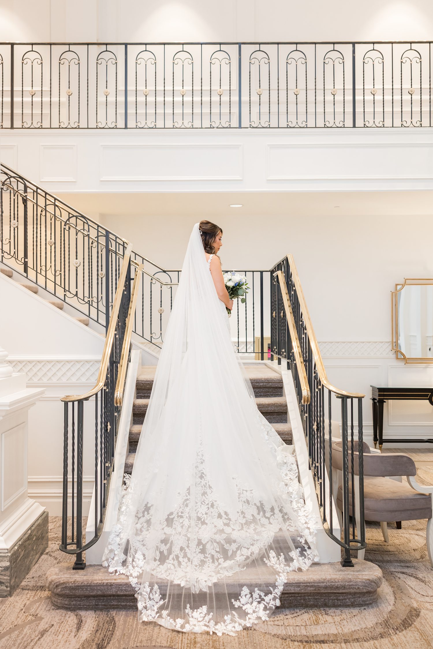 Bride posing on grand staircase in elegant luxury wedding gown
