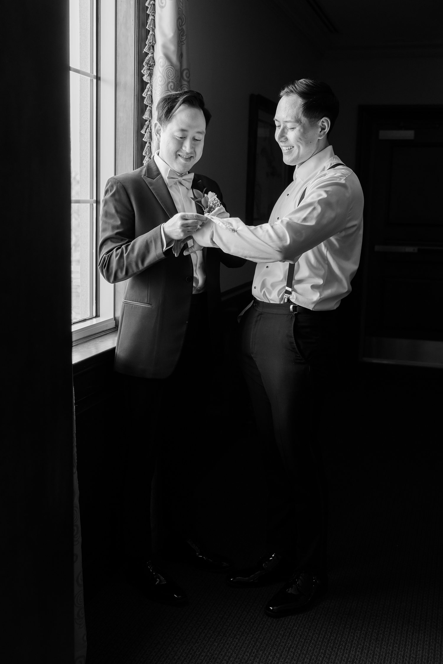 Black and white portrait of groom adjusting cufflinks before ceremony