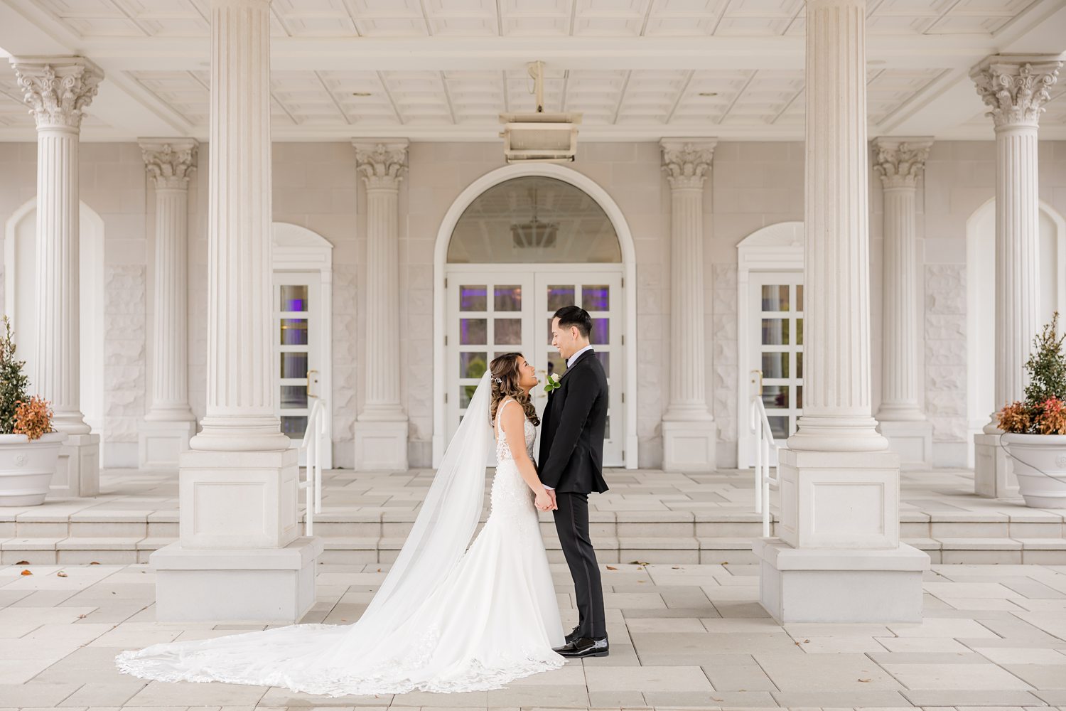 Newlywed couple posing in front of grand luxury wedding venue architecture
