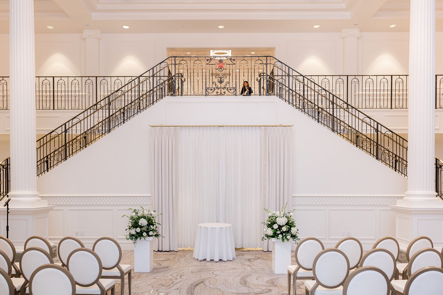 Elegant wedding ceremony setup inside grand ballroom with balcony staircase