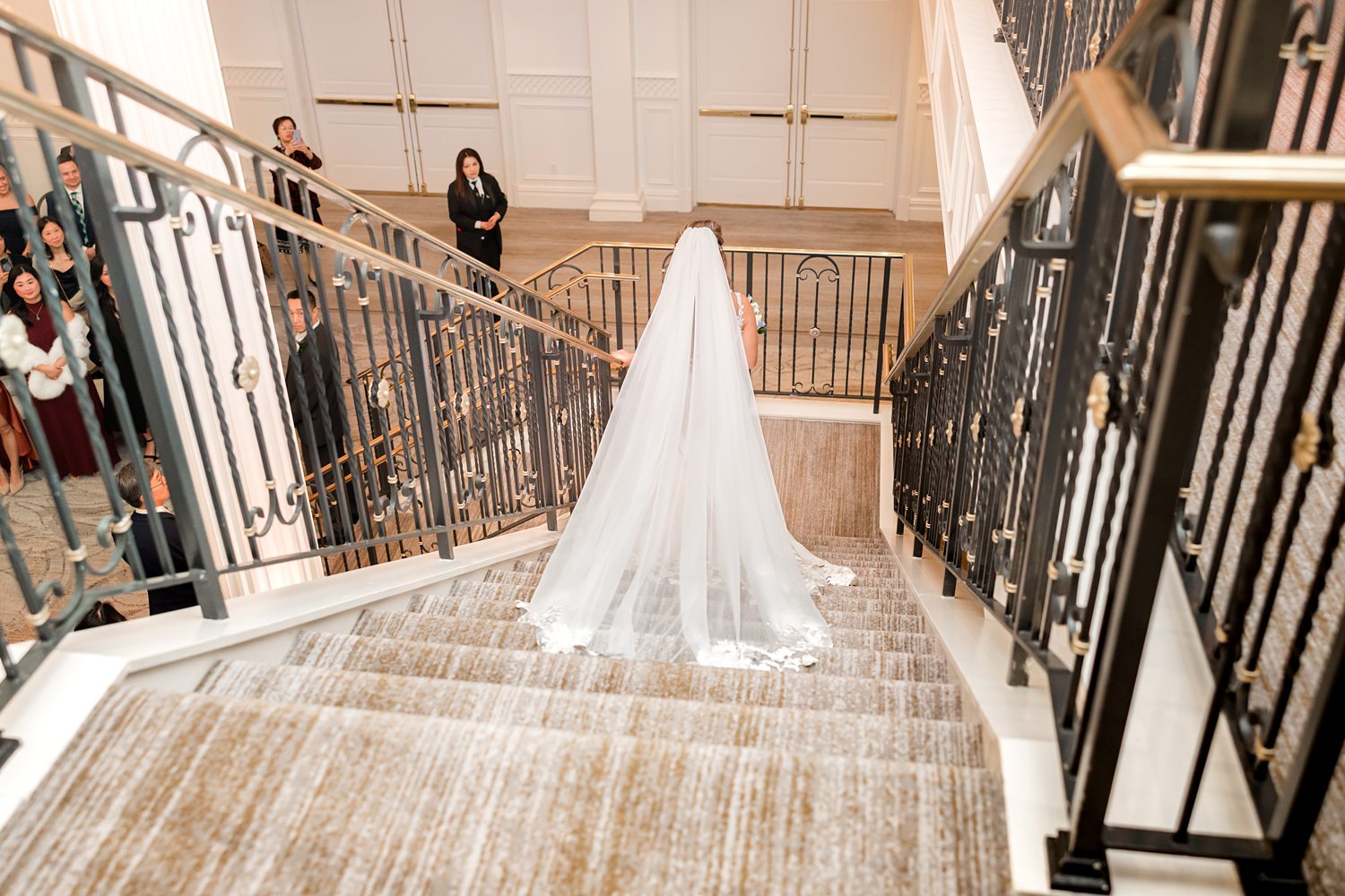 Bride standing on grand staircase with dramatic wedding gown train