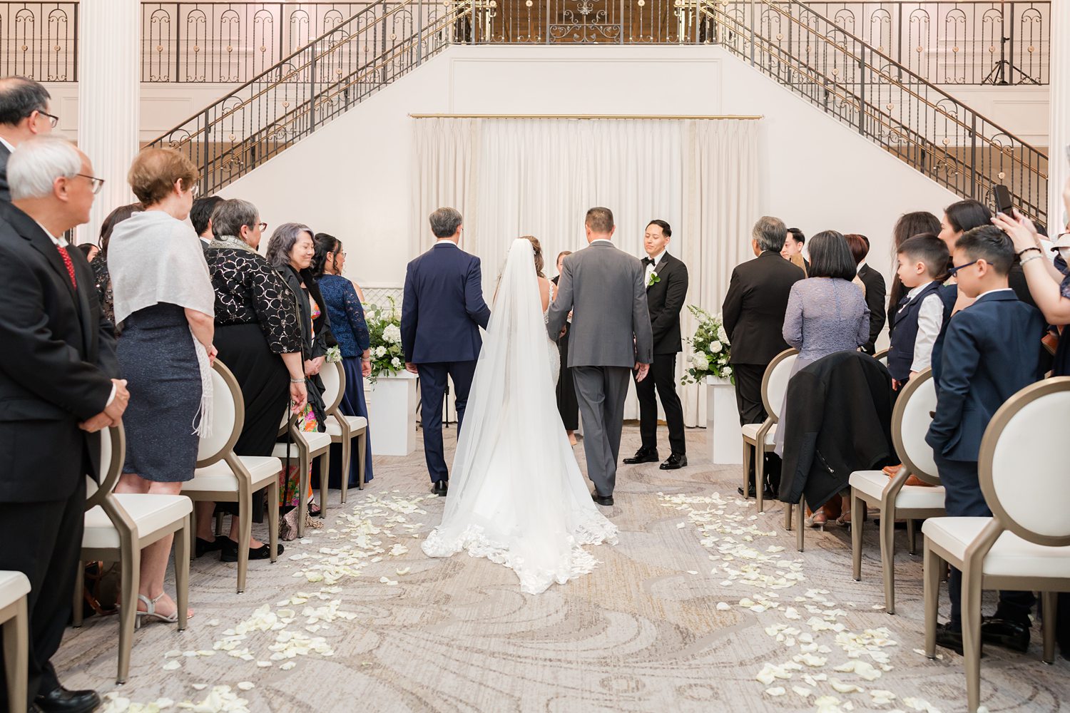 Elegant all-white wedding ceremony at luxury ballroom with bride and groom at altar