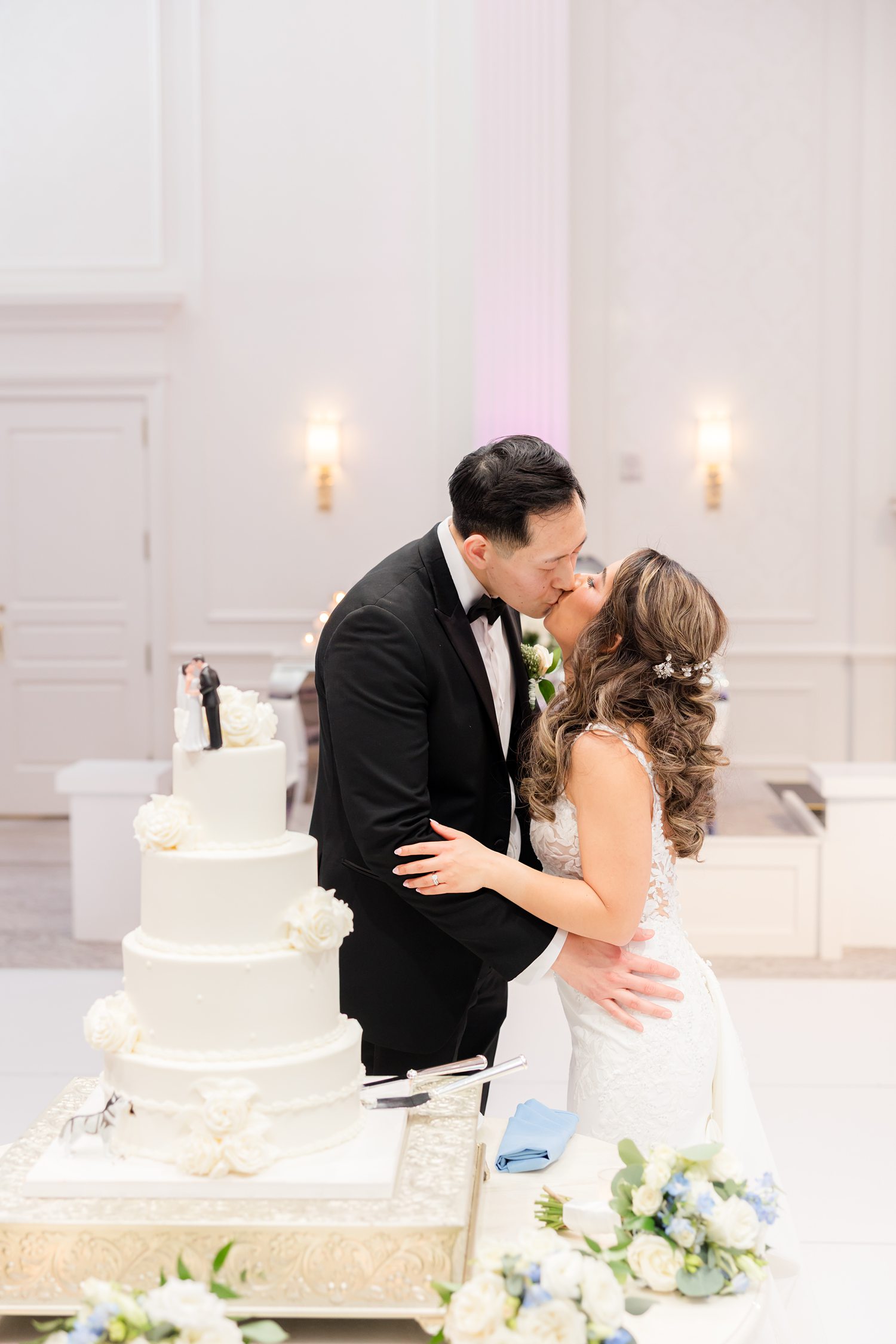 Newlyweds sharing intimate moment beside luxury wedding cake