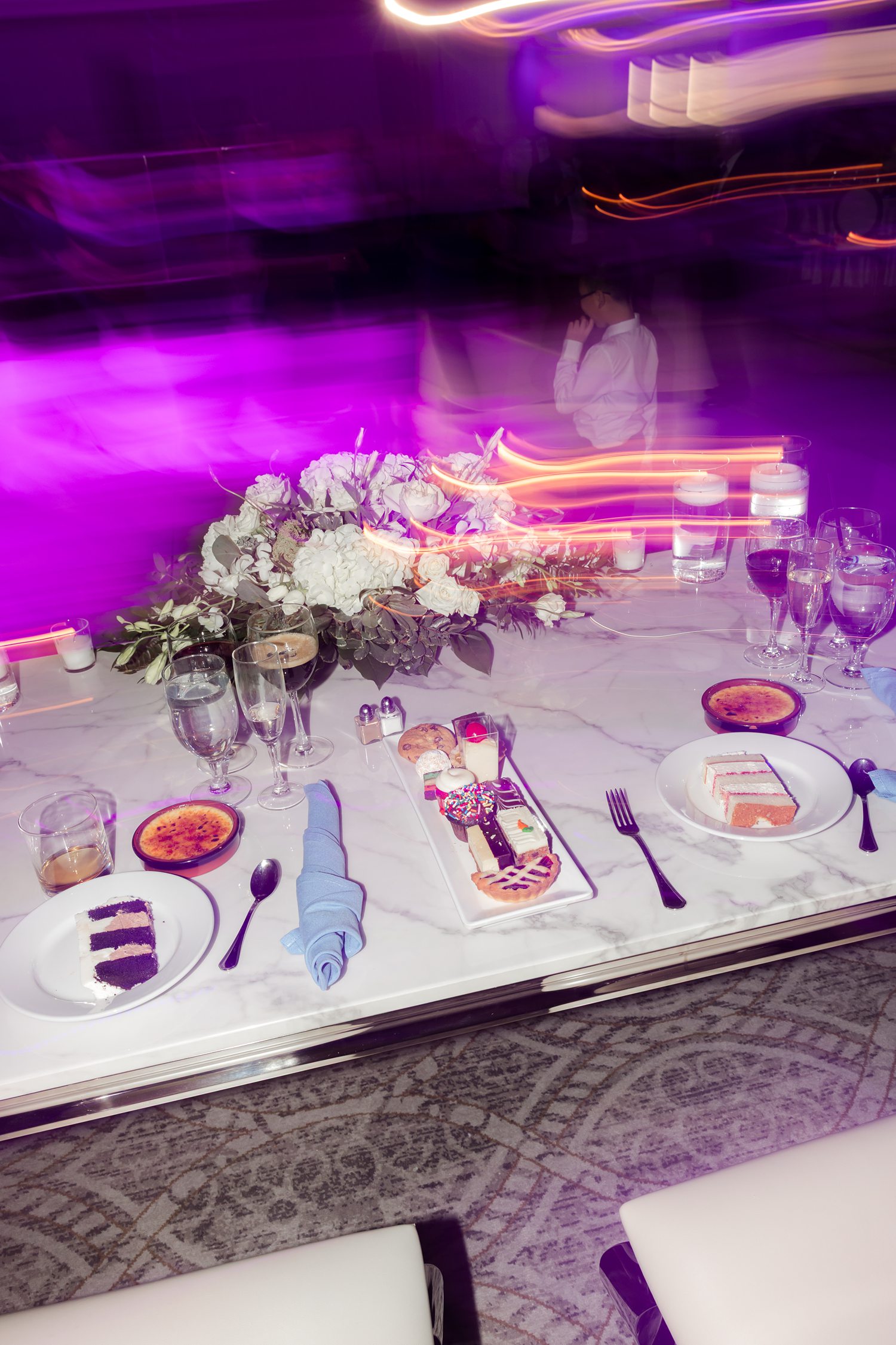 Purple lit wedding reception table styling with floral centerpiece and candles